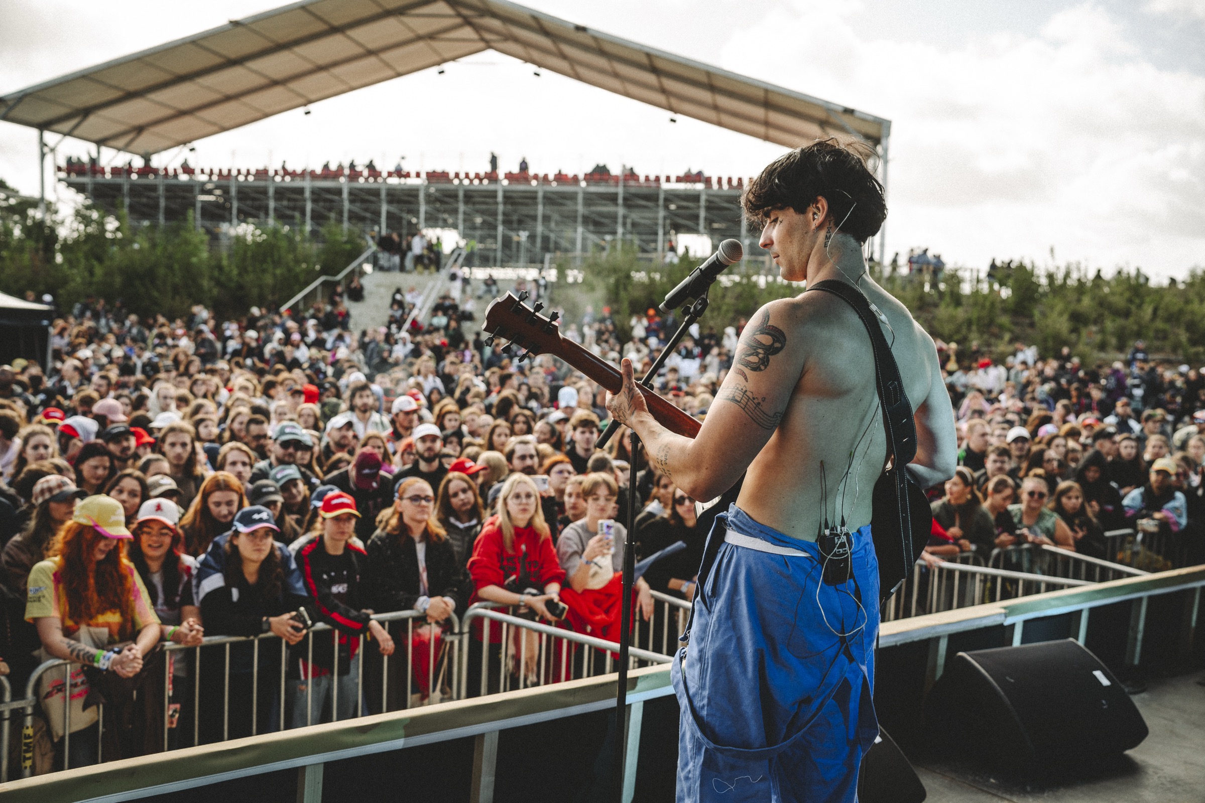 Axel Gregorcik singing and playing guitar on stage, facing the crowd.